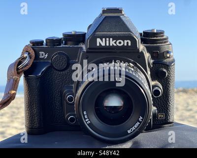 Photo de face d'un reflex numérique classique Nikon DF DSLR sur un tableau de bord de voiture avec fond de brèche. Banque D'Images