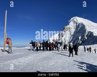 Les touristes sur Jungfraujoch attendent en ligne pour prendre des photos avec drapeau suisse, alpes bernoises, Suisse Banque D'Images