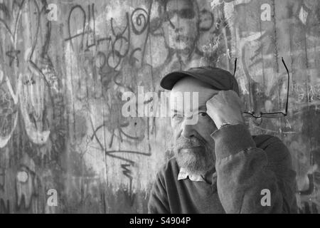 Portrait monochrome de l'homme âgé contre le mur de graffiti Banque D'Images