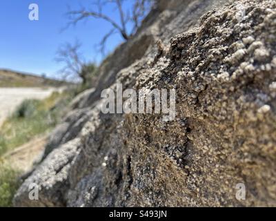 Vue rapprochée des roches avec fond flou, y compris autoroute partielle dans le désert, ciel bleu au-dessus, Californie du Sud, États-Unis Banque D'Images