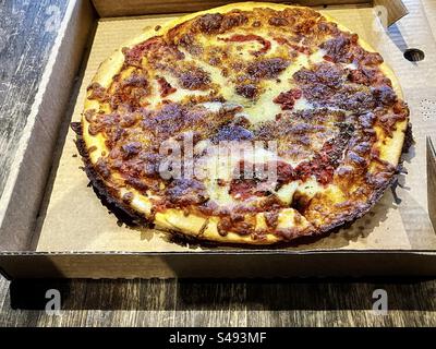 Gros plan de pizza margherita à emporter dans une boîte ouverte sur une table en bois. Banque D'Images