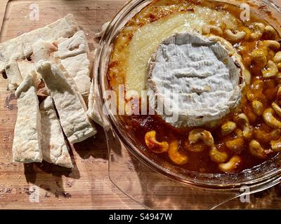 Camembert cuit au four avec conserve d'abricot et noix de cajou, servi avec des doigts de pain Pitta grillés. Banque D'Images