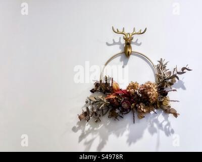 Couronne de vacances de Noël avec fleurs séchées et feuillage sur mur blanc avec espace de copie. Banque D'Images