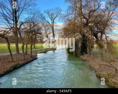 Paysage hivernal avec rivière qui coule à travers le parc de la ville de jardin anglais à Munich, Allemagne. Banque D'Images