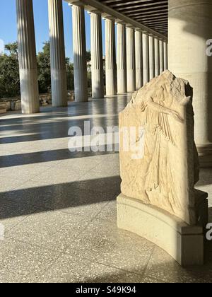 Une ancienne sculpture en relief en marbre se dresse sous la colonnade du Stoa d'Attalos, qui fait partie de l'Agora antique à Athènes, en Grèce. Le site historique Banque D'Images