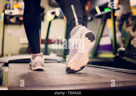 Close up chaussures femme pieds jambes musclées d'exécution sur un tapis roulant d'entraînement à la salle de sport de remise en forme. Voir les chaussures de course, douceur, sol en caoutchouc Banque D'Images