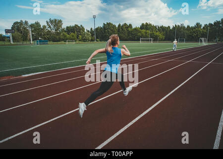 Jeune femme fitness runner s'exécutant sur la piste du stade. Dans le stade d'athlétisme Banque D'Images