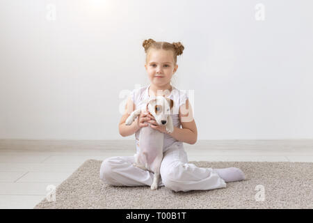 Les gens, les enfants et les animaux domestiques concept - petit enfant fille gisant sur le sol avec mignon chiot Jack Russell Terrier Banque D'Images