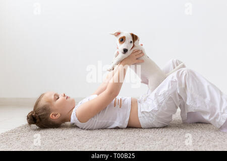 Les enfants, animaux domestiques et animaux - concept fille enfant jouer avec son Jack Russell Terrier puppy à l'intérieur Banque D'Images