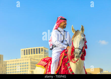 Doha, Qatar - 20 Février 2019 : agent de police en uniforme du Qatar 1940 traditionnel blanc équitation chevaux arabes au square de Souq Waqif dans une journée ensoleillée Banque D'Images