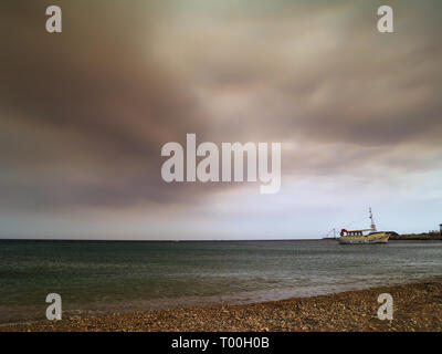 L'île de Rhodes stone beach et bateau de croisière. Nuage de fumée de feu de forêt au-dessus de l'eau. Banque D'Images