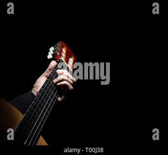 Close up avec une main jouant de la guitare espagnole sur fond noir. Banque D'Images
