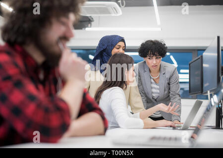 Jeune entreprise multiethnics équipe de développeurs logiciels travaillent ensemble à l'aide d'ordinateur portable et ordinateur de bureau lors de l'écriture de code de programmation moderne à st Banque D'Images