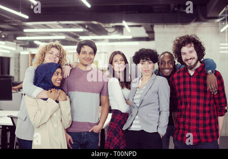 Portrait de jeune entreprise multiethnics excité équipe de développeurs logiciels et permanent à la caméra à tout en célébrant la réussite à démarrage moderne Banque D'Images