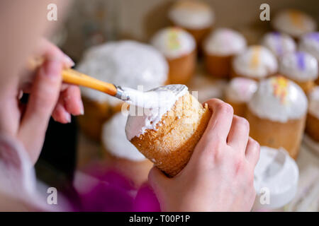 Brosses d'un boulanger un liquide sucre fouettée cerise sur le sommet d'un gâteau de Pâques traditionnel fabriqué à partir de pâte et cuit dans des formes cylindriques pour décorer les t Banque D'Images
