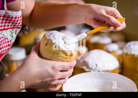 Un boulanger dans un liquide brosses tablier sucre fouettée cerise sur le dessus de gâteau de Pâques traditionnel fabriqué à partir de pâte et cuit dans des formes cylindriques à decorat Banque D'Images