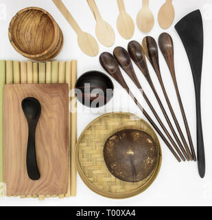 Série de vaisselle en bois exotique sur fond blanc. Ensemble composé de noix de coco, de bambou et de palmier, Tasses, bols, cuillères, spatule Banque D'Images