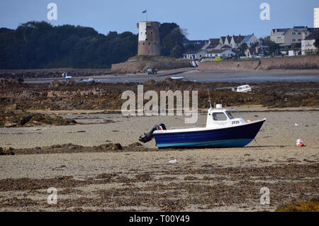 Un bateau sur la plage à marée basse dans la baie de St Clément avec La Rocque Tower en arrière-plan sur l'île de Jersey, Îles britanniques, Royaume-Uni. Banque D'Images