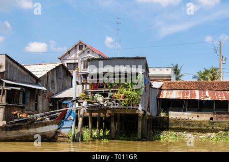 Vietnamien typique cabane en tôle des maisons sur pilotis sur les bords de la rivière Co Chien dans le Delta du Mékong. À Cai Be, province de Tien Giang, Vietnam, Asie Banque D'Images