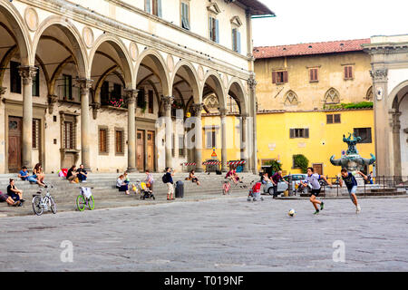 Adolescents kick a socerball autour de la Piazza della Santissima Annunziata, à Florence, dans la région de Toscane, en Italie. Banque D'Images