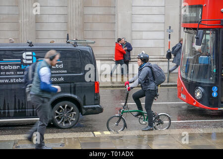 Rue urbaine avec un cycliste, des piétons, une camionnette et un bus londonien un jour de pluie Banque D'Images