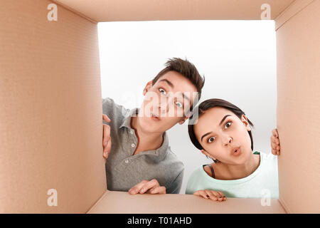 Cheerful teen couple déballage, ouverture en carton et à l'intérieur avec un sourire sur leurs visages. Ils sont enchantés par la vitesse de livraison des marchandises. Les émotions humaines et les expressions faciales concept Banque D'Images