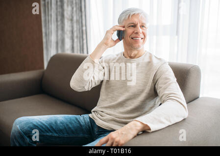 Homme adulte à la maison parler par téléphone mobile Banque D'Images