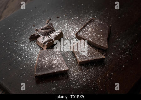 Morceaux de chocolat amer à la fleur de sel sur la surface en bois sombre. Des collations bio. Banque D'Images