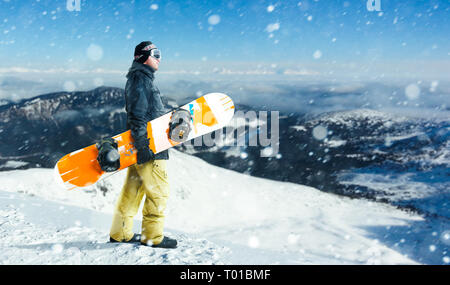 Snowboarder mâle se dresse au sommet de la montagne Banque D'Images