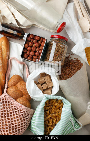 Repas dans des sacs de coton eco, le verre et le papier d'emballage sur table dans la cuisine de marché. zéro déchets shopping concept. ban plastique, le pain, les noix, le sucre, Banque D'Images