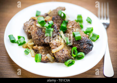 Foie frit avec des oignons dans une assiette sur un sol en bois Banque D'Images