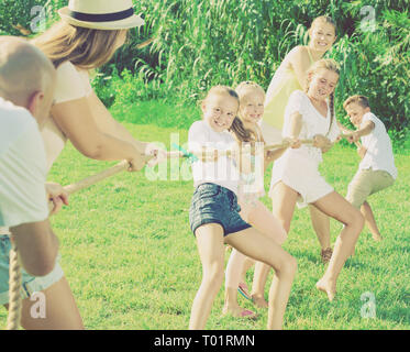 Les enfants avec les parents jouer remorqueur de la guerre durant les jeux en plein air aux beaux jours Banque D'Images