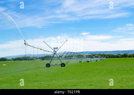 Grand système d'irrigation à pivot central d'exécution sur une ferme à Central Otago, Nouvelle-Zélande fournissant de la distribution de l'eau pour les terres agricoles à la gestion des pâturages Banque D'Images