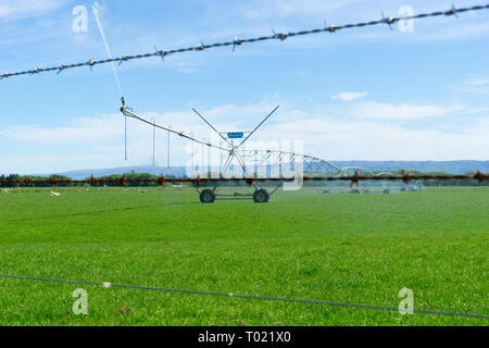 De l'autre côté de barbelés un grand système d'irrigation à pivot central d'exécution sur une ferme à Central Otago, Nouvelle-Zélande fournissant de la distribution de l'eau Banque D'Images