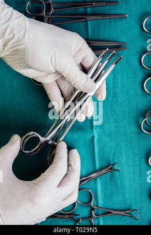 Chirurgien travaillant en salle d'opération, les mains avec des gants holding scissors, conceptual image, composition verticale Banque D'Images