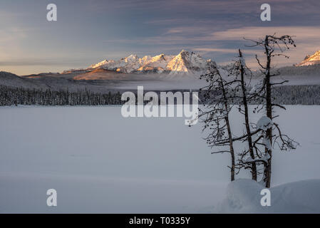 Nuages de compensation nourrir une chaîne de montagnes au-delà d'un lac couvert de neige dans l'Idaho Banque D'Images