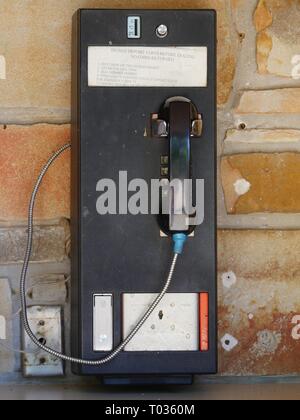 Téléphone public vintage monté à l'extérieur d'un magasin exigeant des pièces Banque D'Images