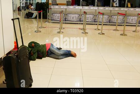 KUALA LUMPUR, MALAISIE—MARS 2016: Une femme dort pieds nus sur les planchers brillants du terminal Bersepadu Selatan à Bandar Tasik Banque D'Images