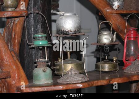 Lampes, cuisinières et bouilloires à thé millésimés au-dessus d'une étagère en bois épaisse Banque D'Images