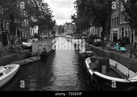 Amsterdam - canal latéral de la rivière Amstel.Black & White shot avec vintage green vieux scooter. Banque D'Images