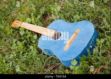 Belle espagnole classique acoustique Guitare denim personnalisés couché sur l'herbe verte piscine Banque D'Images