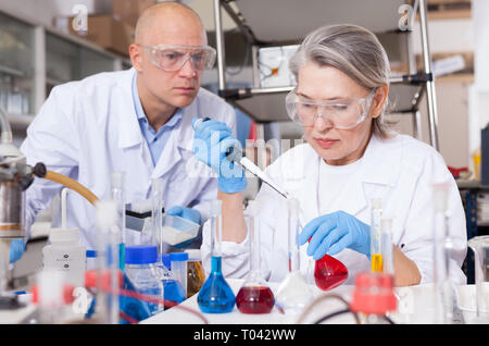 Deux chimistes professionnels travaillant en laboratoire, réactifs de mélange en tube à essai avec une pipette de laboratoire Banque D'Images