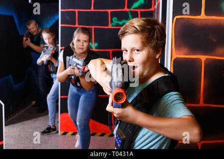 Heureux heureux happy smiling boy positives visant pistolet laser à d'autres joueurs pendant le jeu laser tag in dark room Banque D'Images