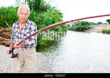 Man positive sur la pêche à la rivière et essayer de prendre du poisson Banque D'Images