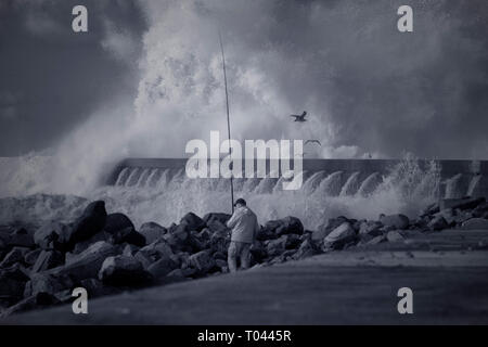 Porto, Portugal - 20 décembre 2015 : pêcheur sportif dans le fleuve Douro, la bouche pendant l'orage. Banque D'Images