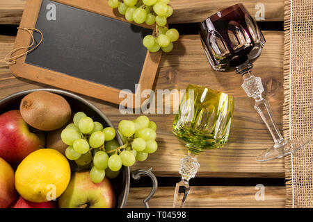 Rummers traditionnel/verres à vin sur planches de bois rustique et organisé de fruits dans un bol, tableau noir et tissu du jute. Menu pour le vin ou d'un restaurant. Banque D'Images