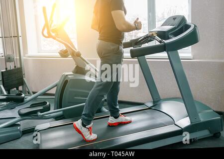Athletic homme musclé en marche sur des tapis roulants dans le sport moderne de sport. Fitness, le sport, la formation, les gens concept Banque D'Images
