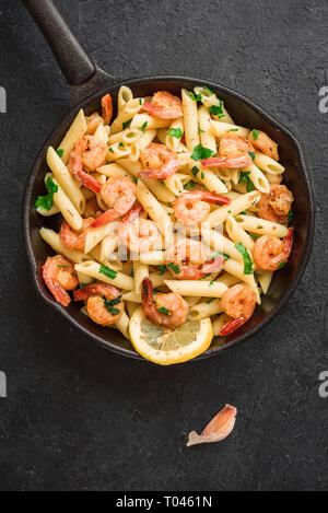 Pâtes penne aux gambas ou crevettes sur noir, vue du dessus, copiez l'espace. Crevettes sautées au citron avec des pâtes, fruits de mer frais. Banque D'Images