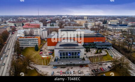 La vue aérienne du grand bâtiment à Tartu avec un toit rouge voitures garées à l'avant et sur le côté de la route avec des voitures qui passent par Banque D'Images