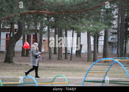 Fille blonde avec ballon rouge en forme de cœur à pied sur Spring Street Banque D'Images